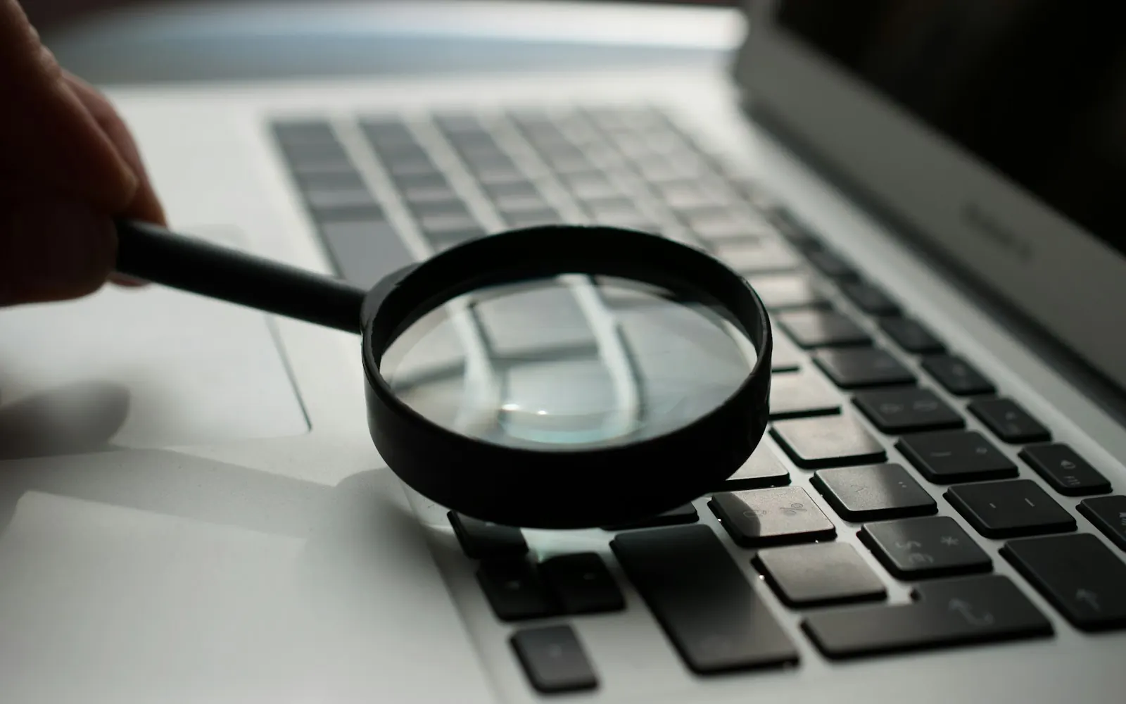 A magnifying glass resting on a laptop keyboard, representing search research for Birmingham businesses