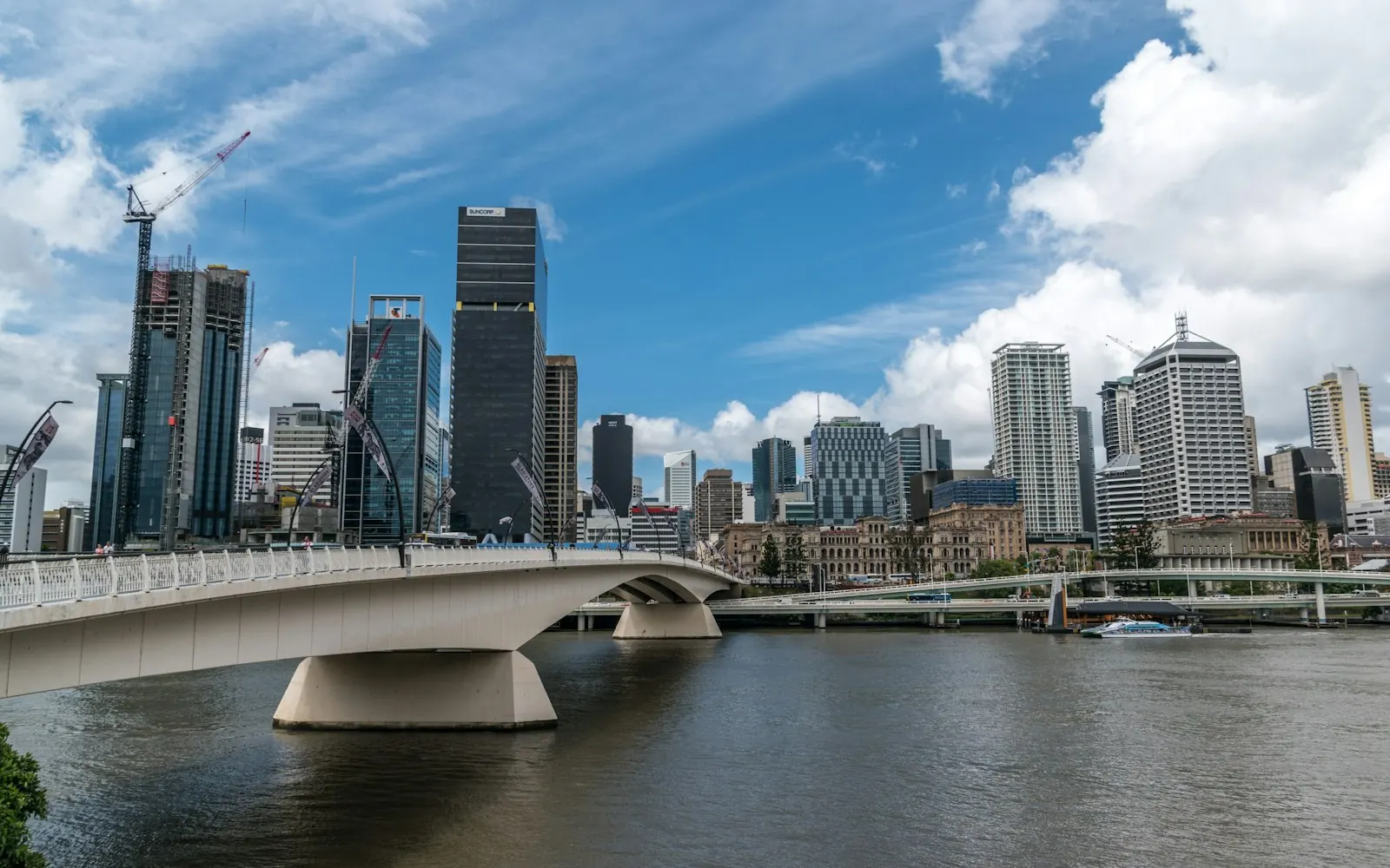 The Brisbane River with a white pedestrian bridge leading towards the CBD skyline