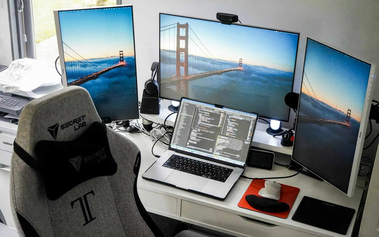 A desk with several monitors showing code for a Brisbane website build in progress