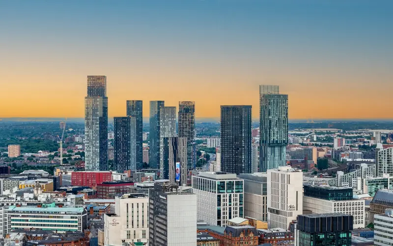 Manchester city centre skyline with modern towers and red brick mills at dusk
