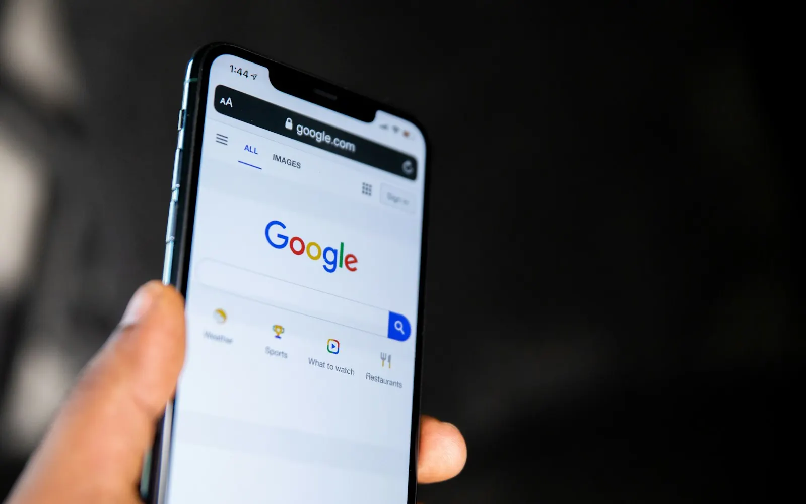 A hand holding a smartphone showing the Google search page, as used by Manchester customers searching locally