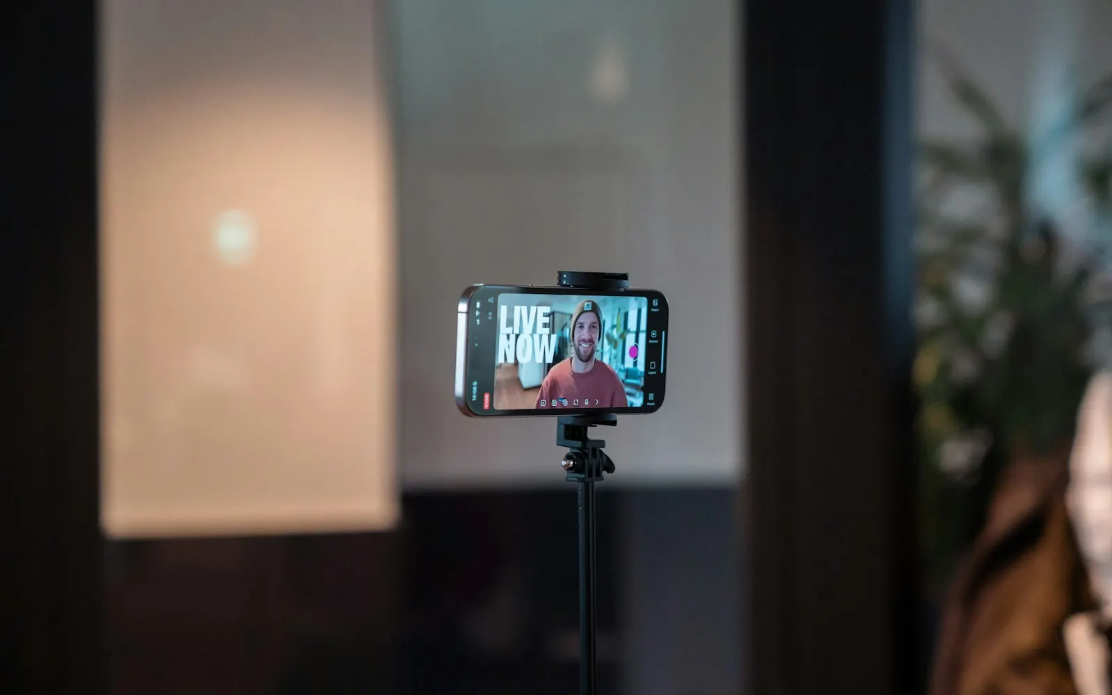 A smartphone on a tripod filming a person in a studio during a social media video shoot