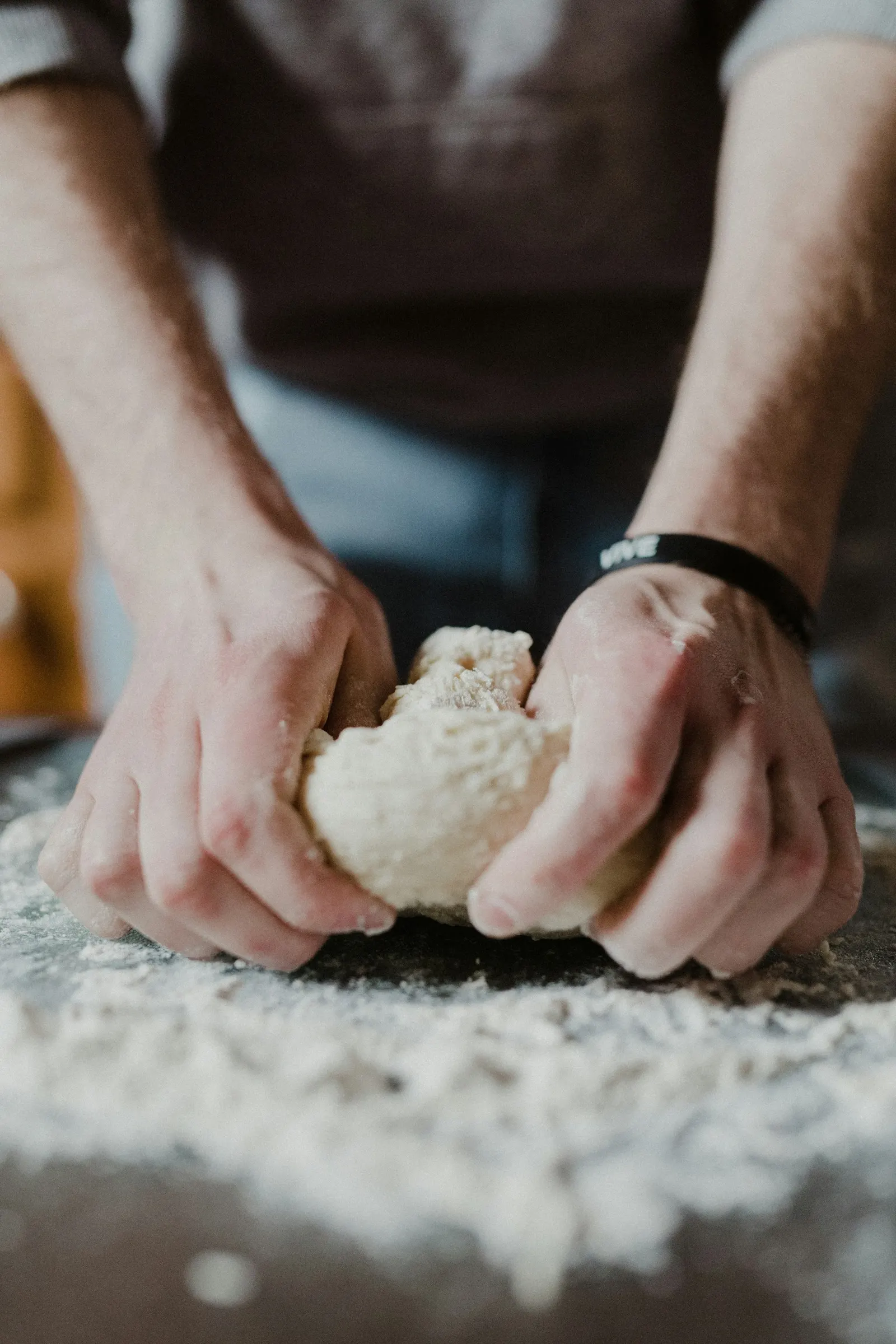 Hands kneading dough on a floured wooden table