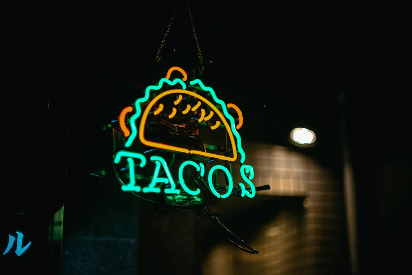 A green neon taco sign glowing at night