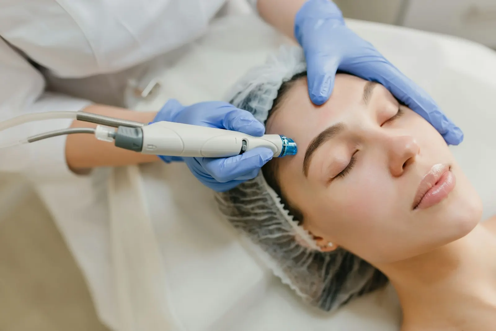 A gloved practitioner using a device during a facial treatment