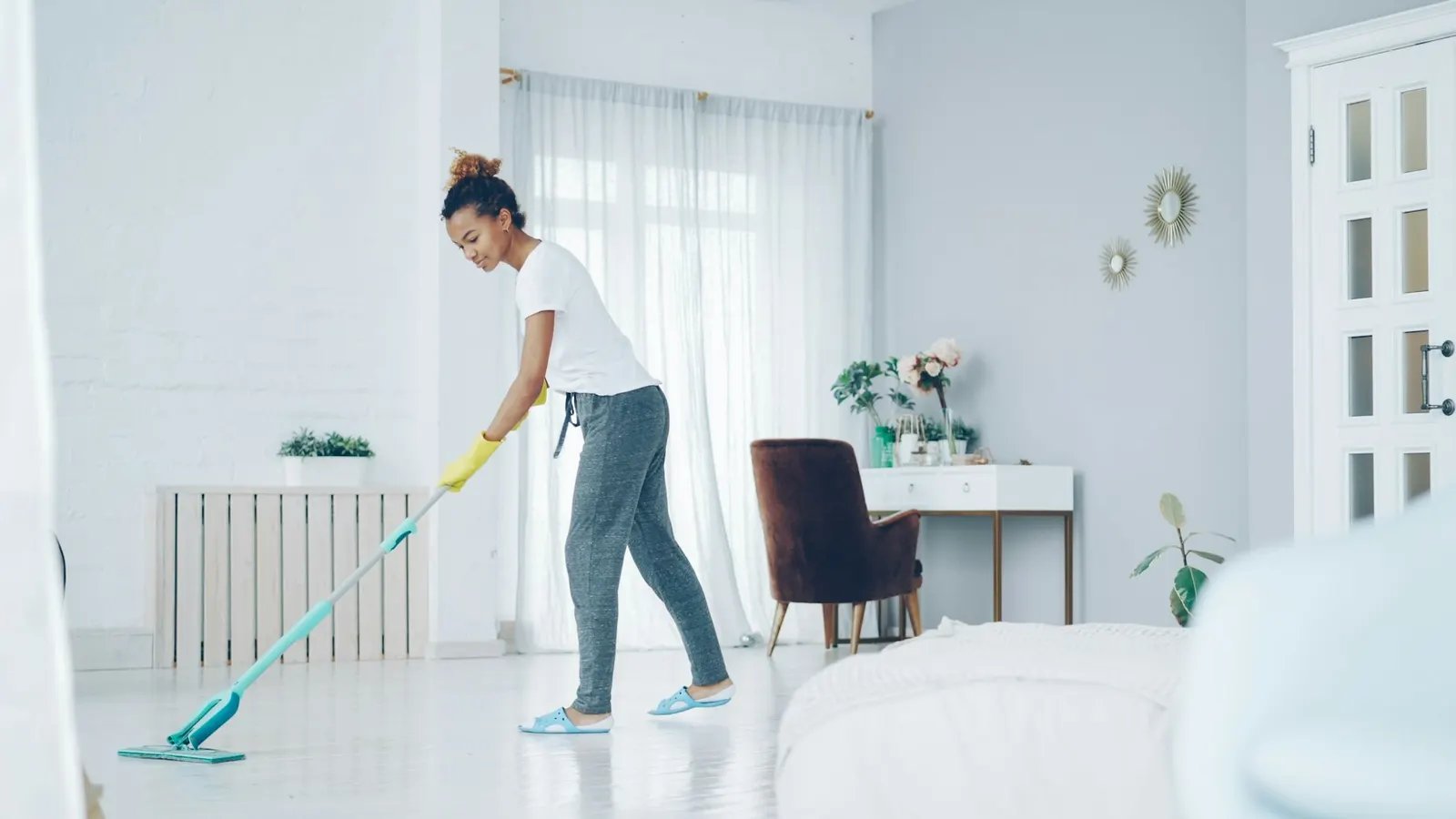 A cleaner mopping the floor of a bright, modern living room