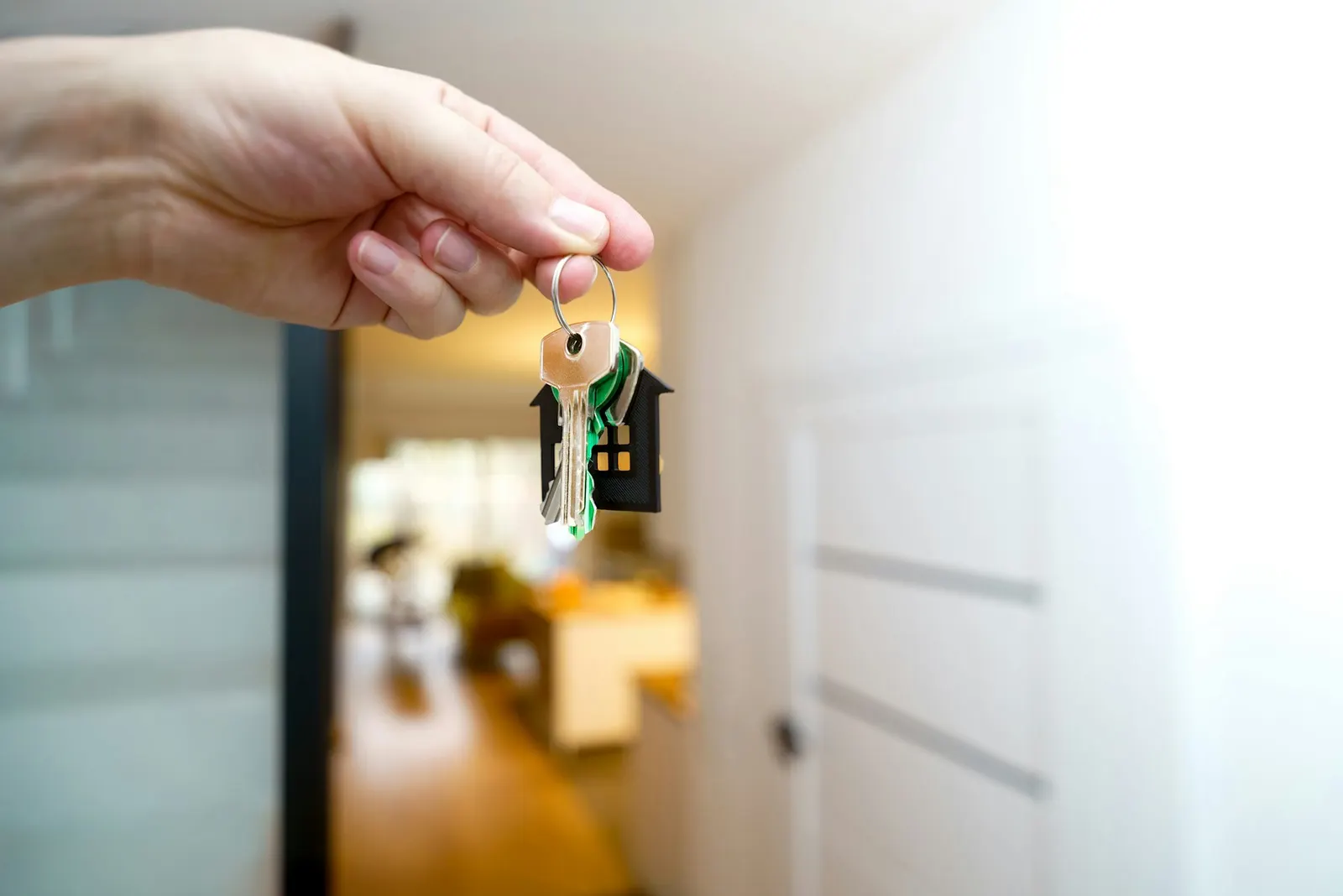 A hand holding house keys in front of a front door