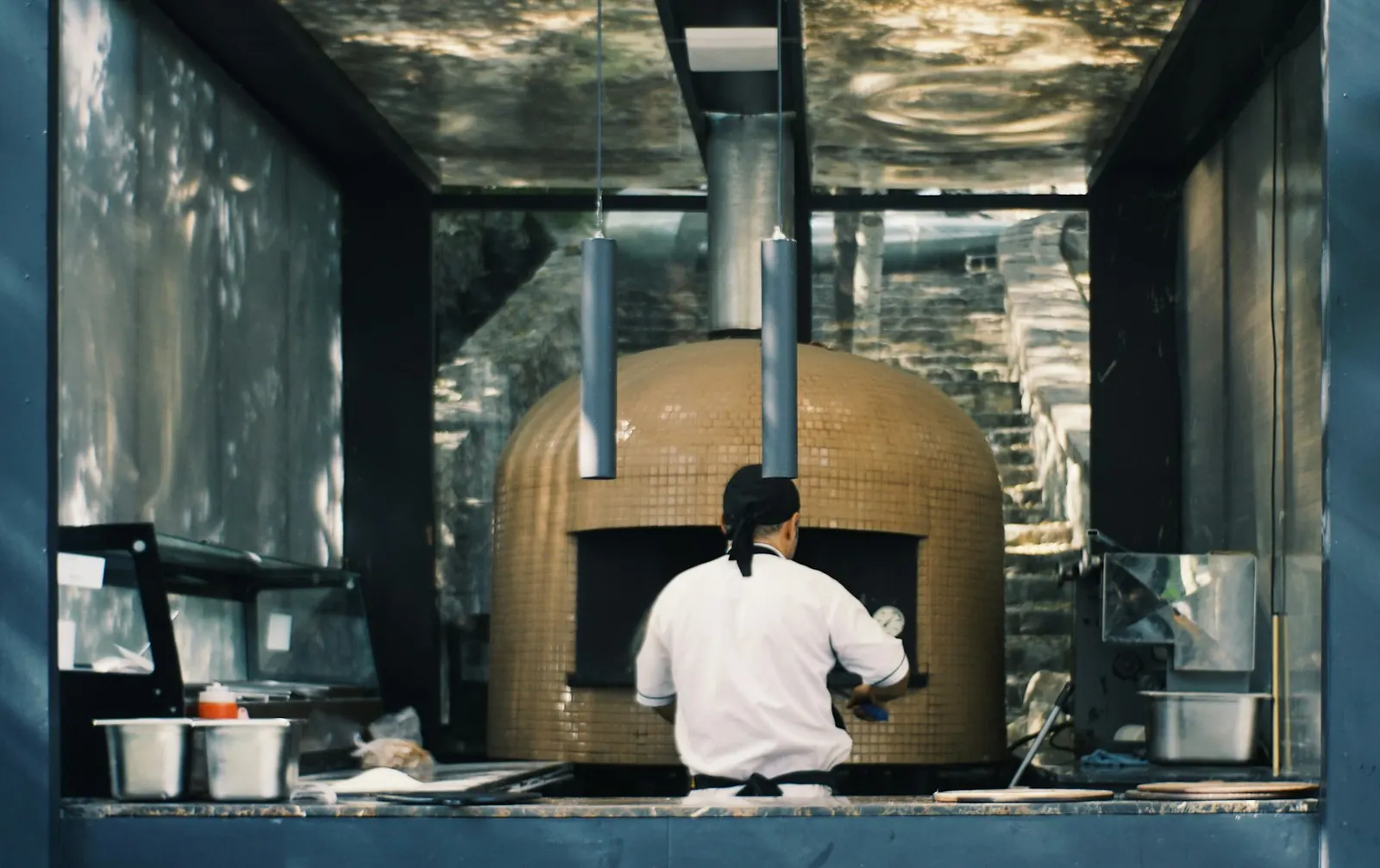 A chef working in front of a large pizza oven
