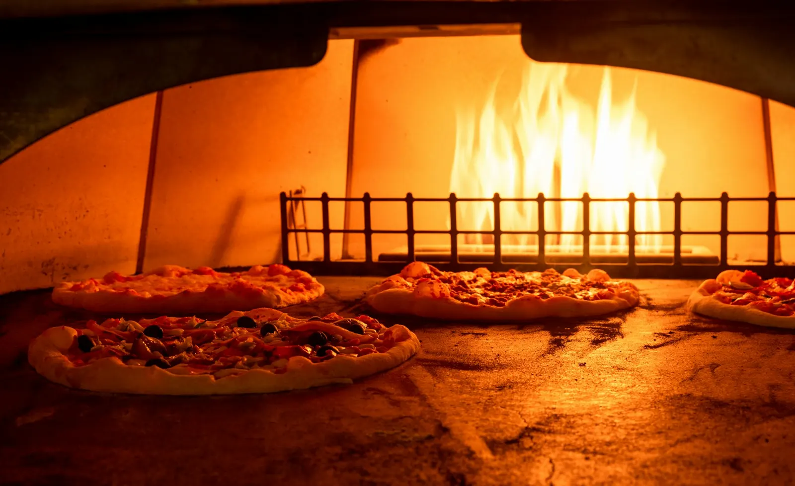 Pizzas baking in a glowing wood-fired oven