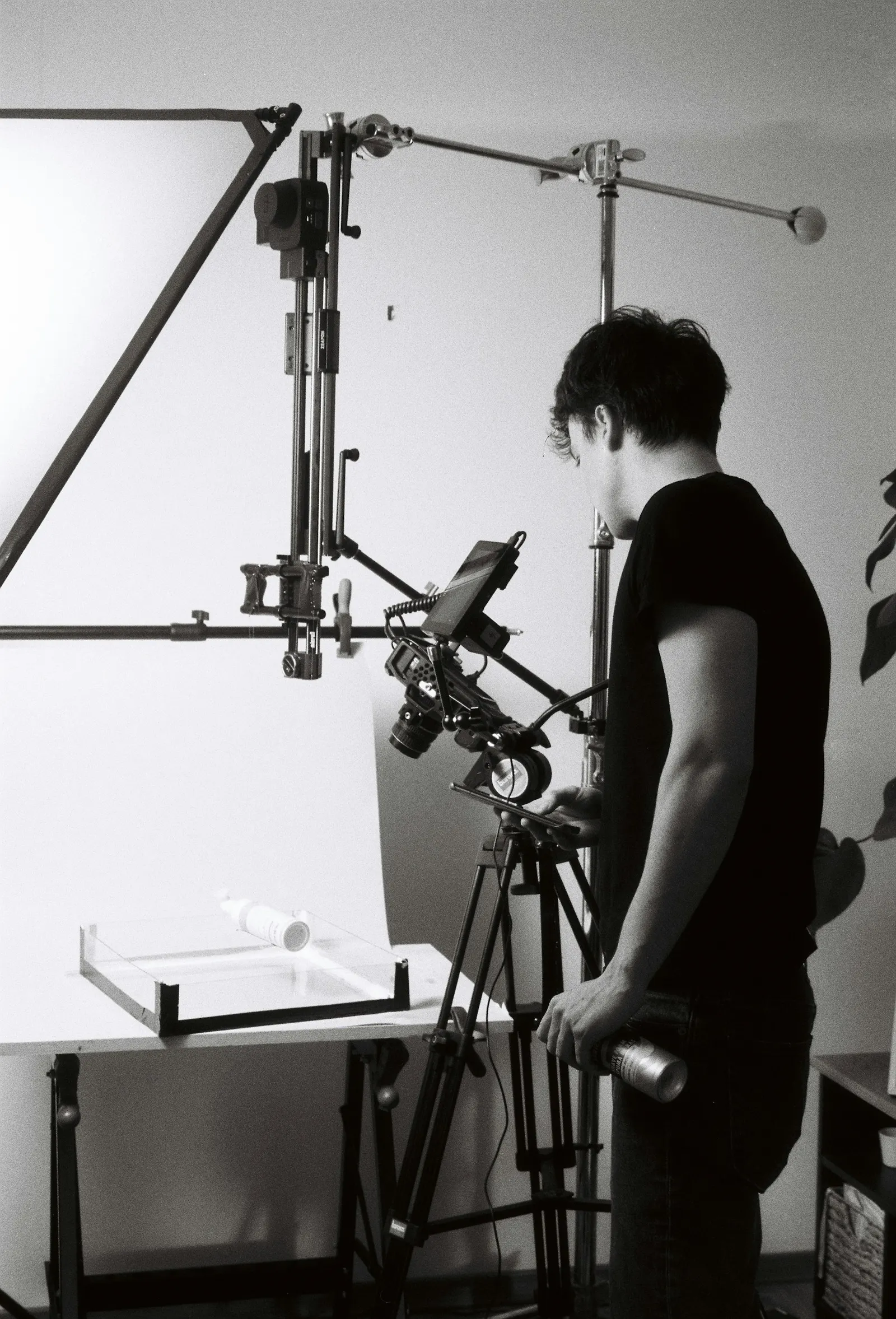Photographer adjusting a camera and lights over a product table in a studio